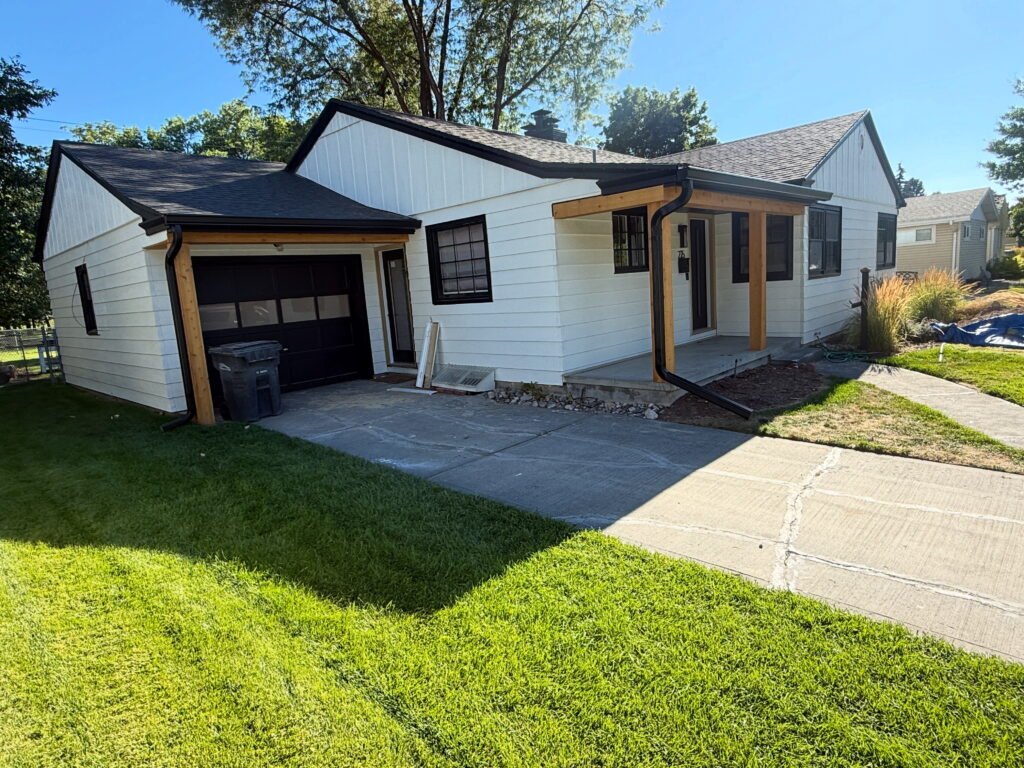 Remodeled white home with black seamless gutters and downspouts, cedar porch posts and attached garage