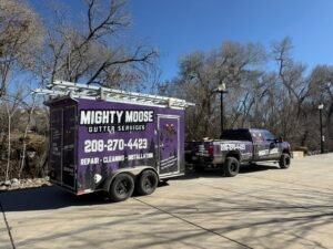 Mighty Moose Gutter Services purple wrapped truck and ladder-rack trailer parked on a driveway